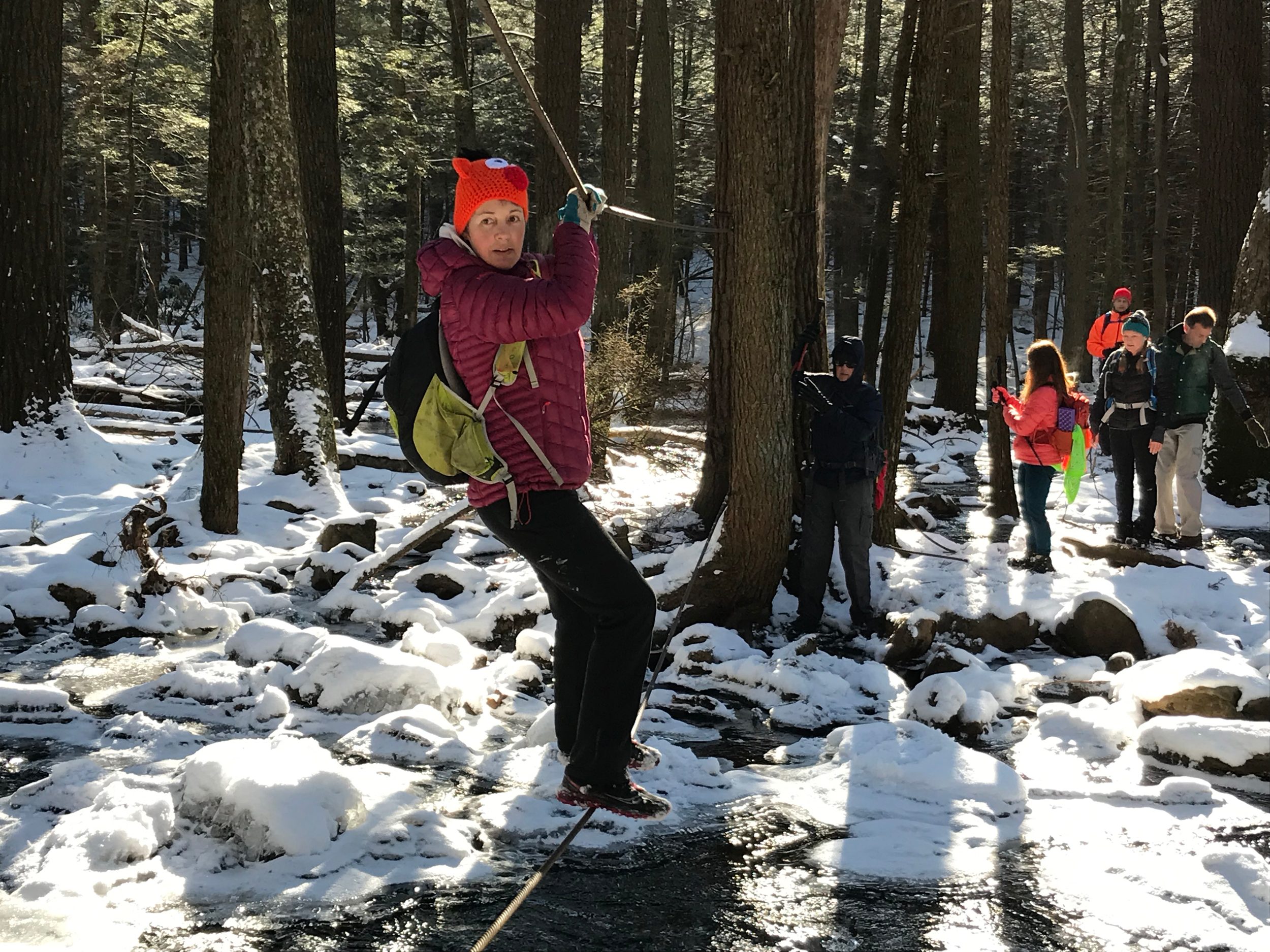 winter hiker crosses stream