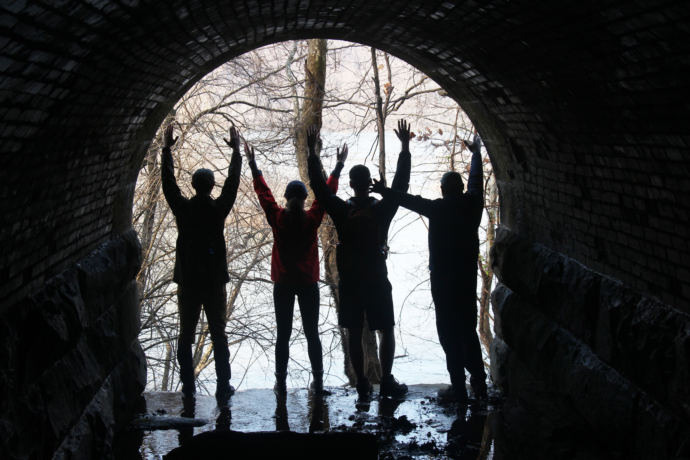 hikers silhouette photo in tunnel